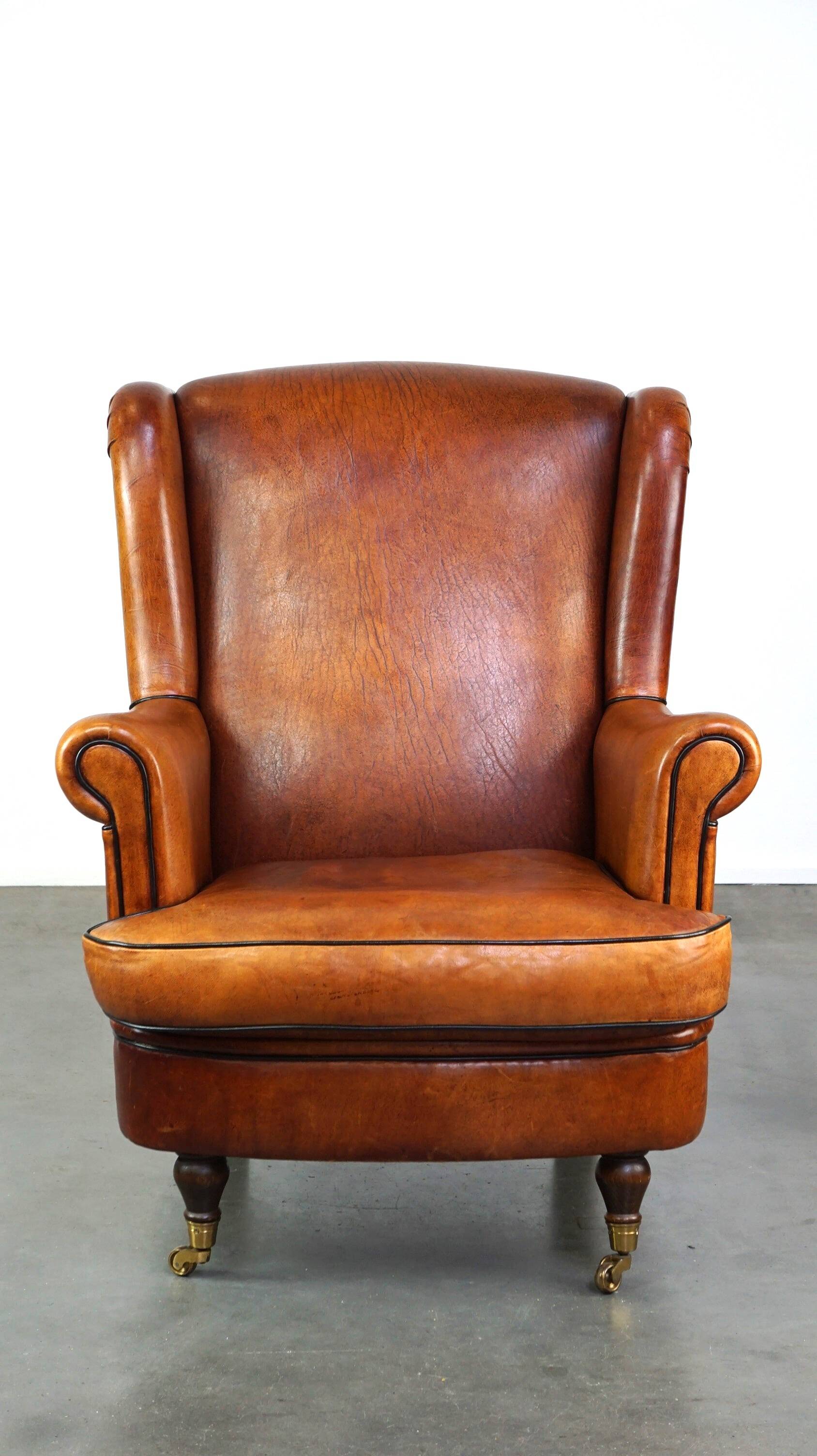 Subtle sheepskin wing chair in good condition on brass front wheels