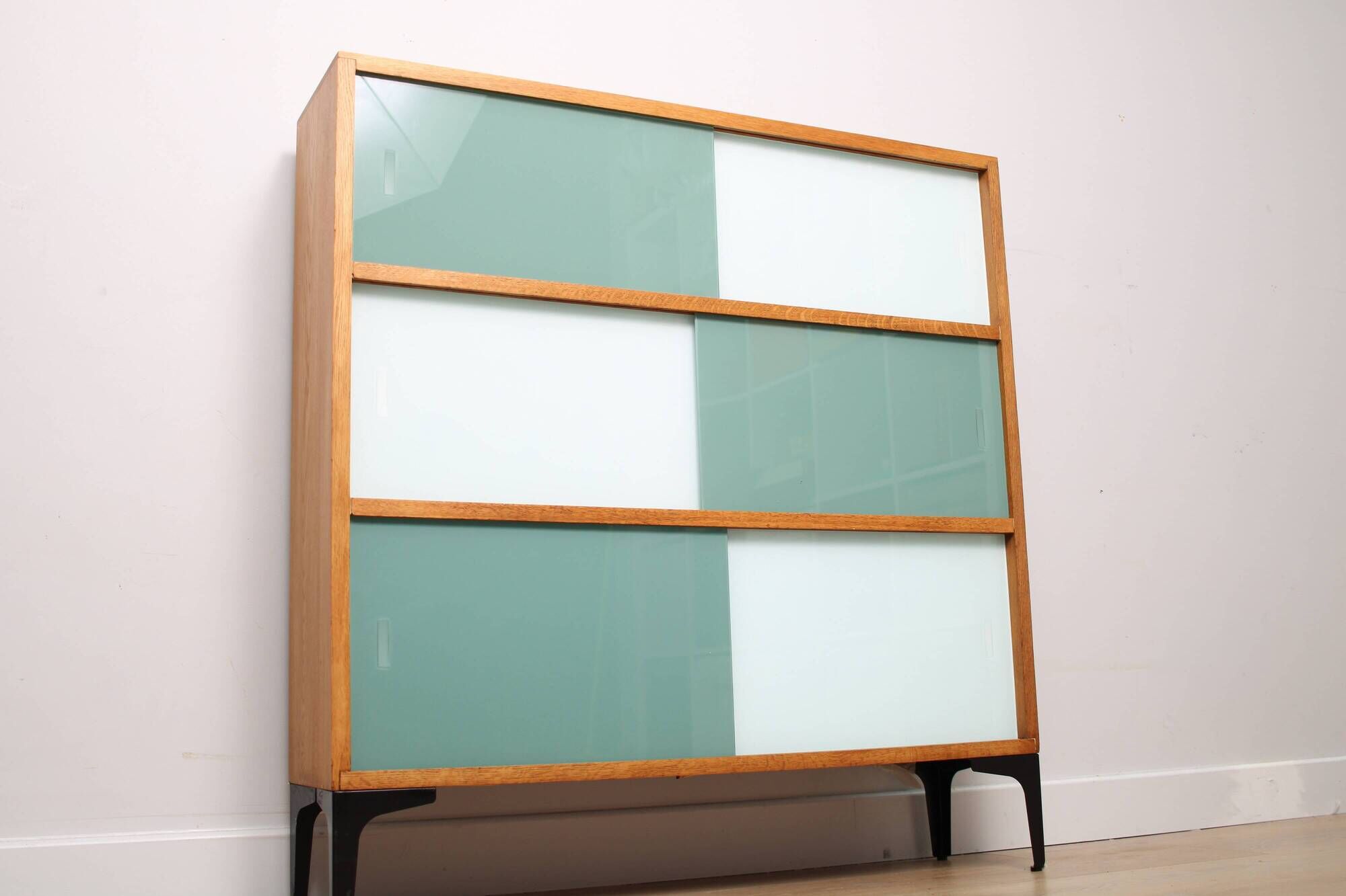 A vintage mid-century 3 tiered bookcase with glass sliding doors