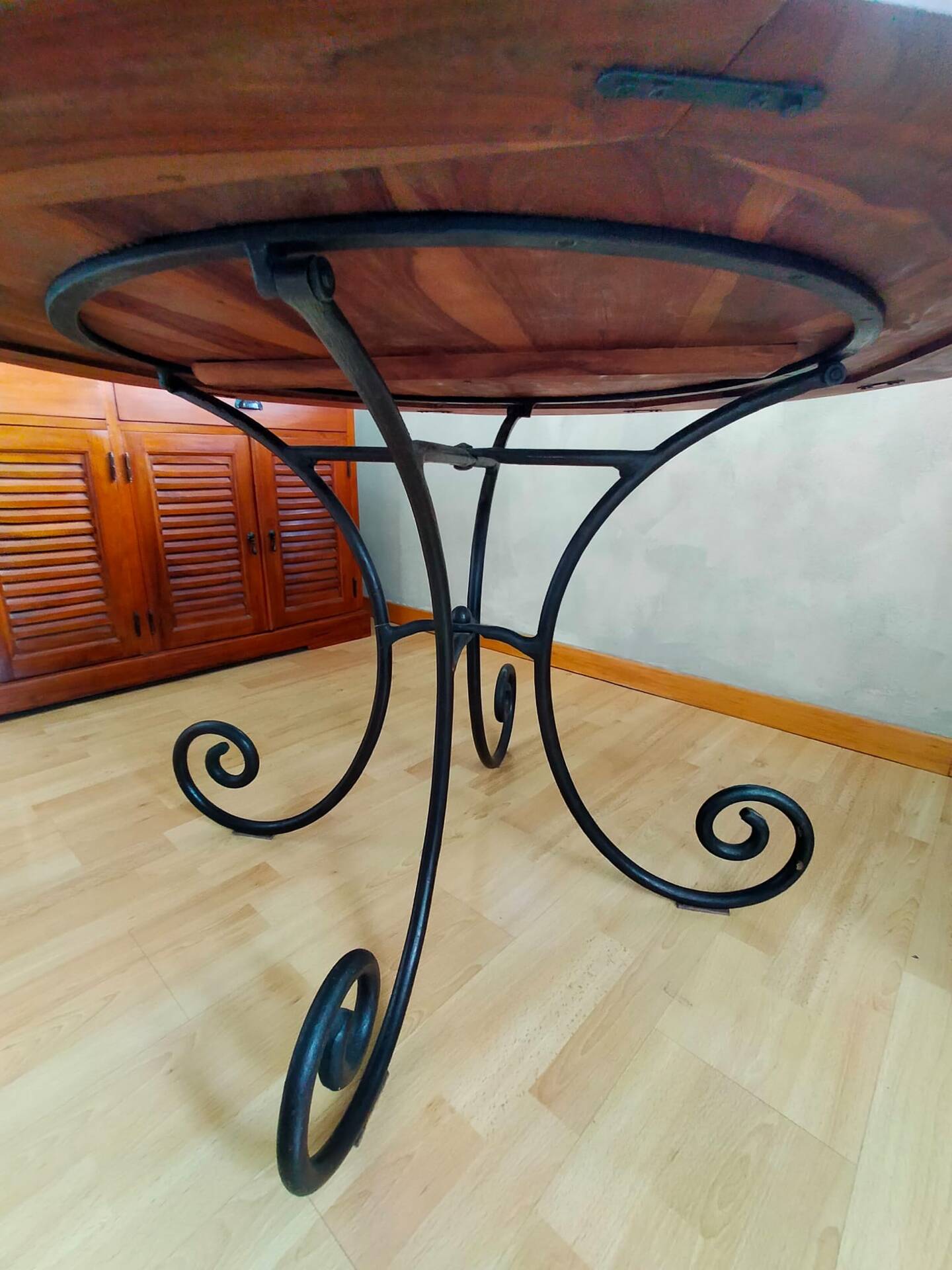 Round wooden table with wrought iron legs.