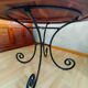 Round wooden table with wrought iron legs.
