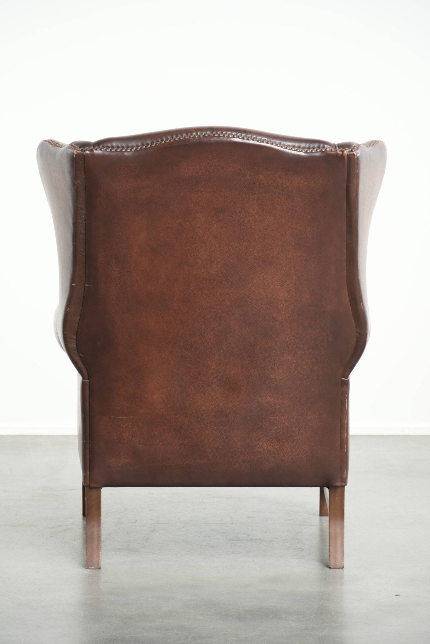 Fauteuil à oreilles en cuir de vache confortable de style anglais avec un look intemporel.
