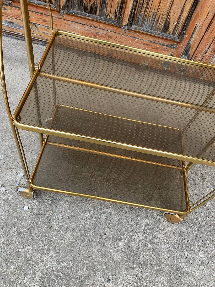 Chariot pliant vintage doré en laiton et plastique fumé à deux plateaux et roulettes