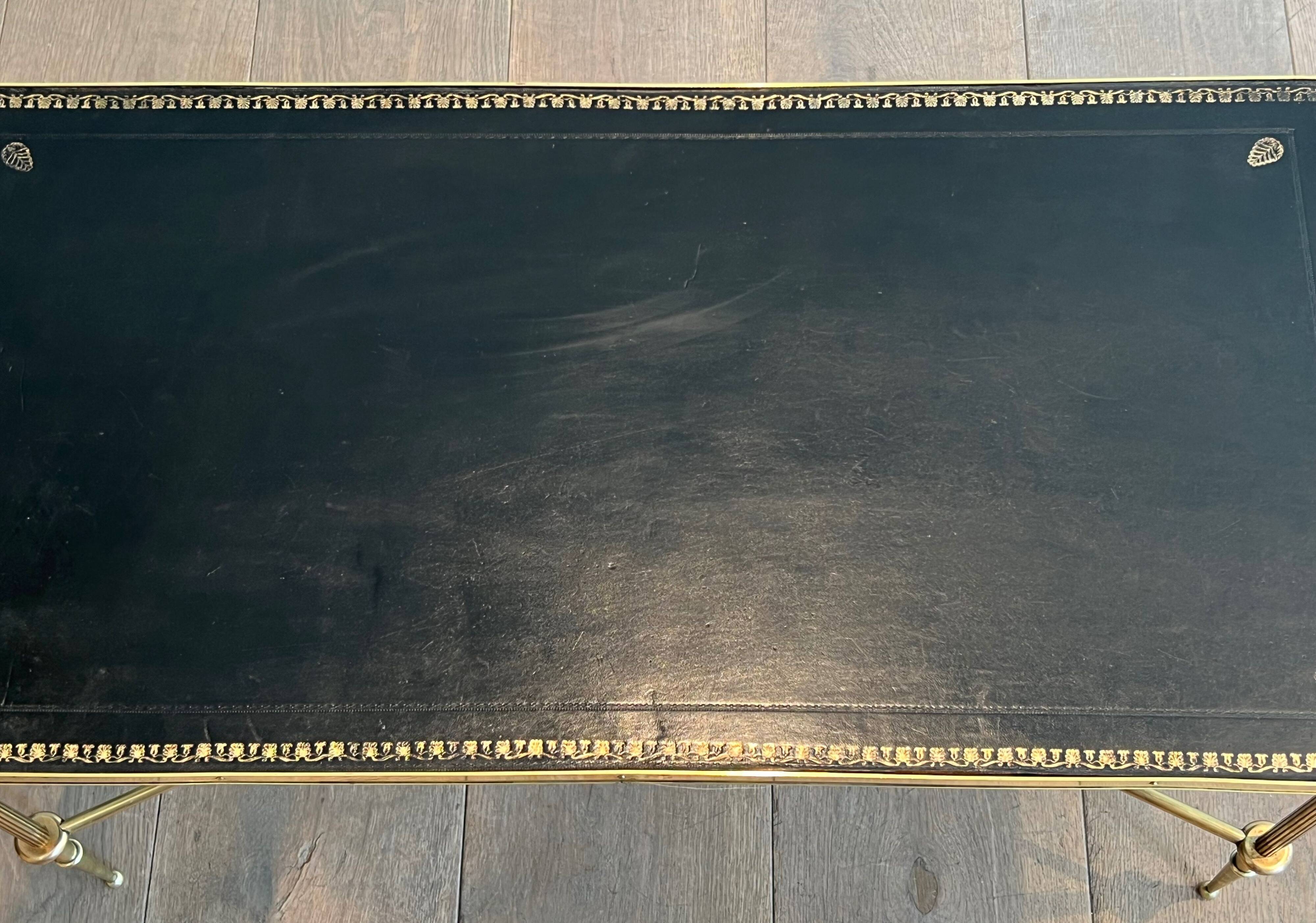 Neoclassical brass coffee table with a black leather top and golden borders from Maison Jansen.