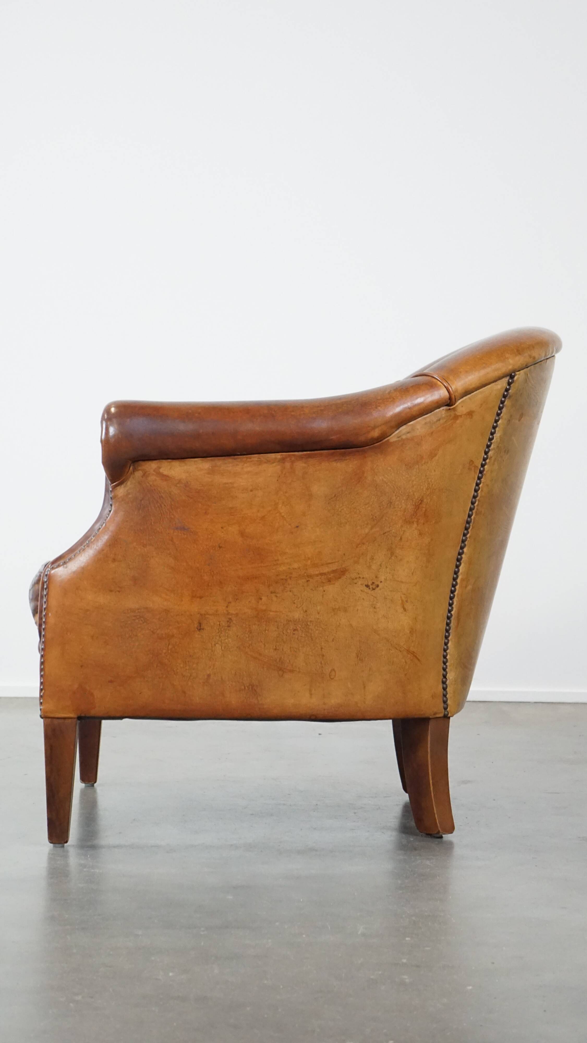 Un fauteuil club robuste mais confortable en cuir de mouton et fini avec des clous décoratifs