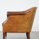 Un fauteuil club robuste mais confortable en cuir de mouton et fini avec des clous décoratifs