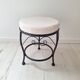 Black iron stool/pouf with its boucle fabric cushion.