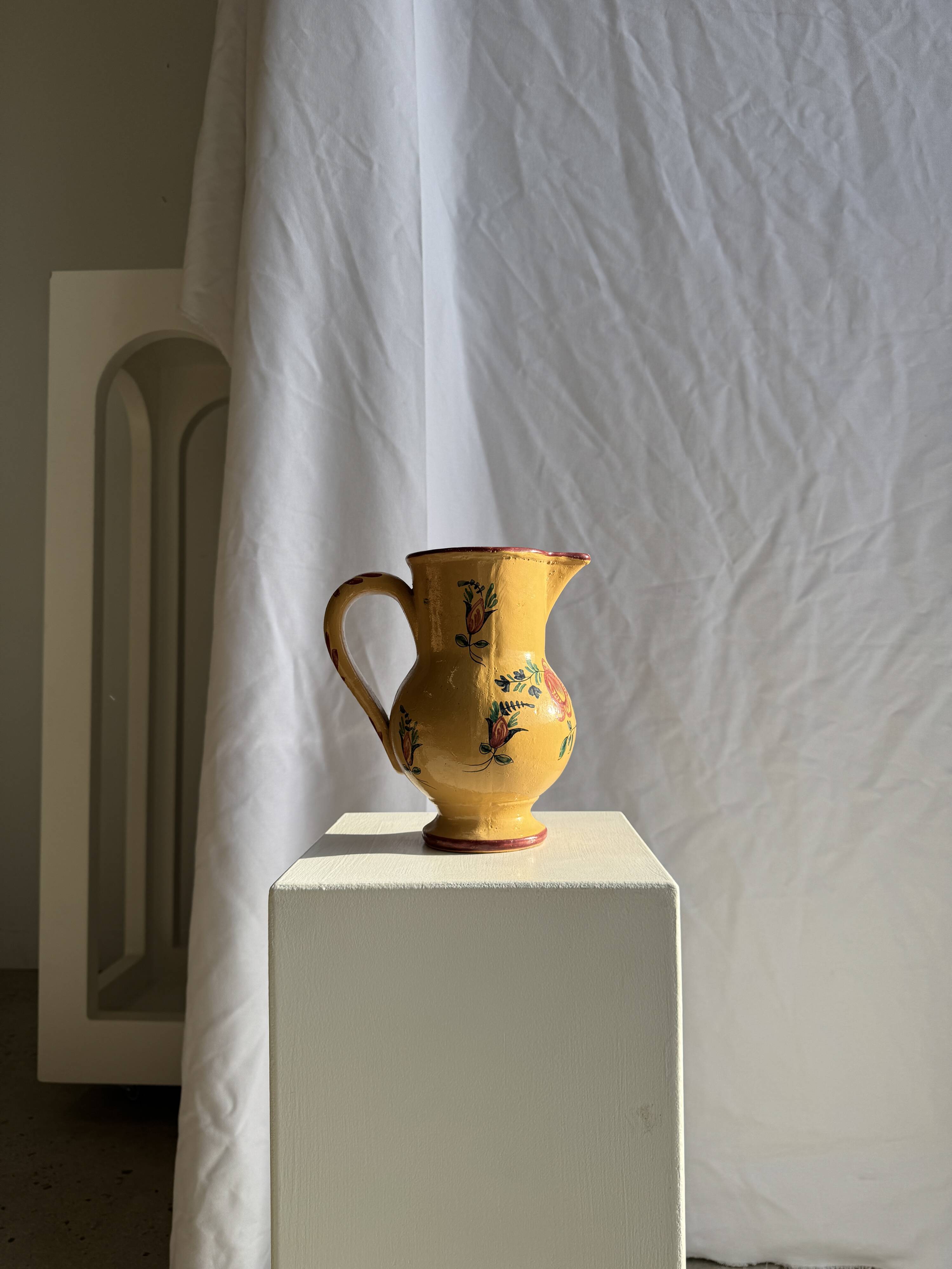 Large antique handmade ochre yellow jug with a pink flower pattern.