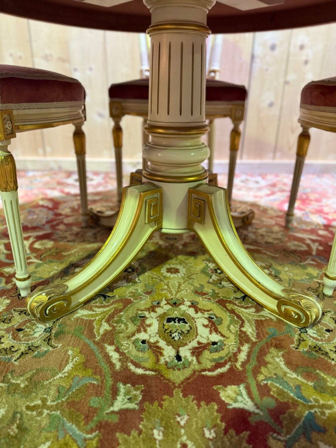 Louis XVI dining room table set with painted wood, gold accents, and pink velvet.