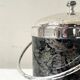 Vintage chrome metal ice bucket with black marbled design, 1970s style.