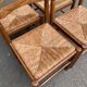 4 solid wood kitchen chairs with straw seats in a country farmhouse style.