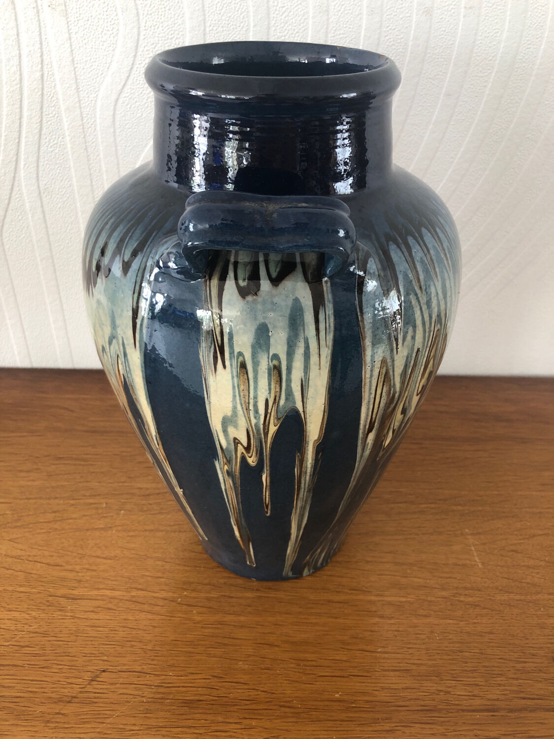 Vase in glazed ceramic decoration drips on blue background