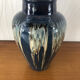 Vase in glazed ceramic decoration drips on blue background
