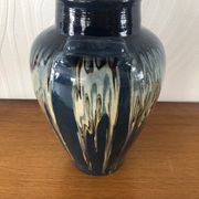 Vase in glazed ceramic decoration drips on blue background