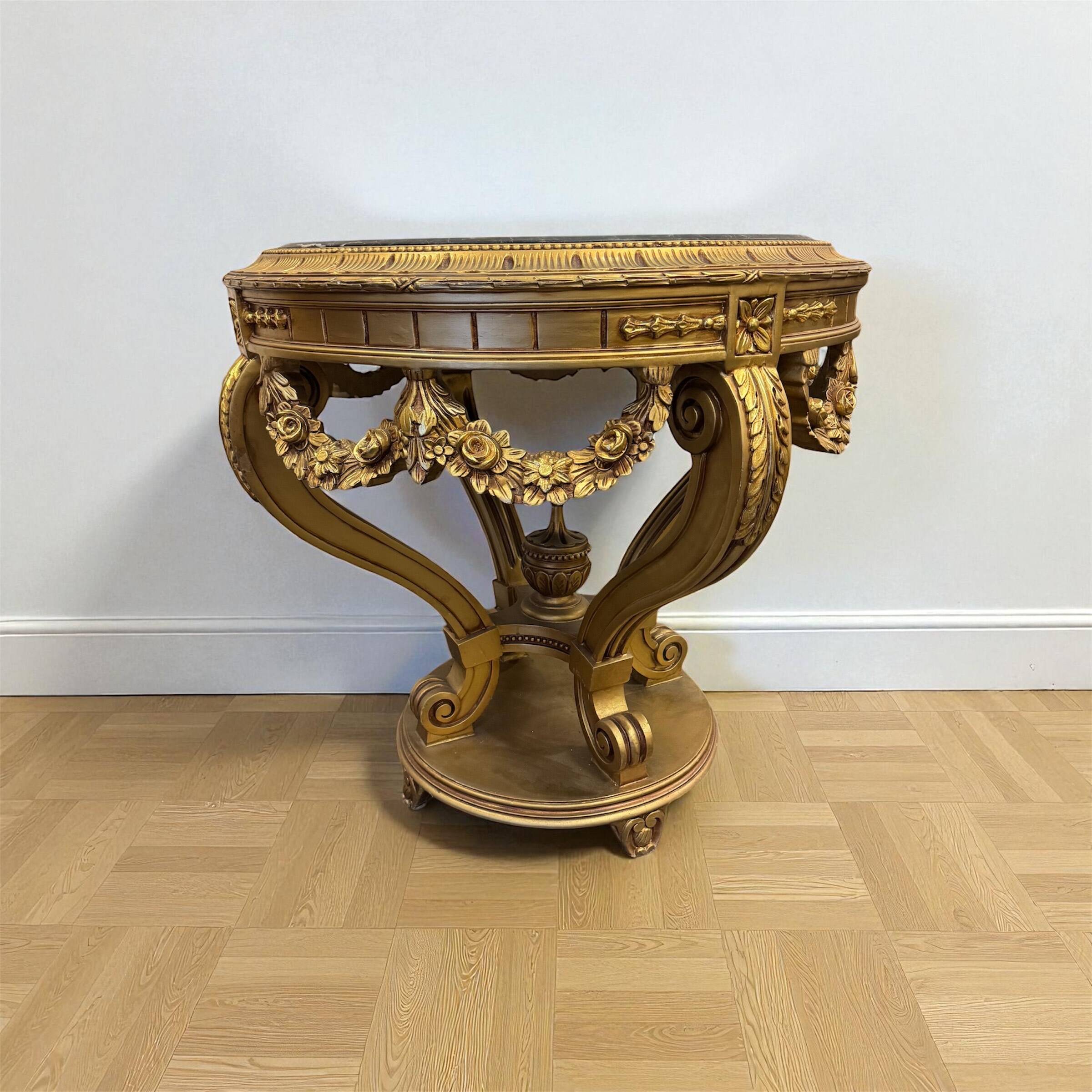 A round Louis XV style table in carved gilt beechwood with a black marble top