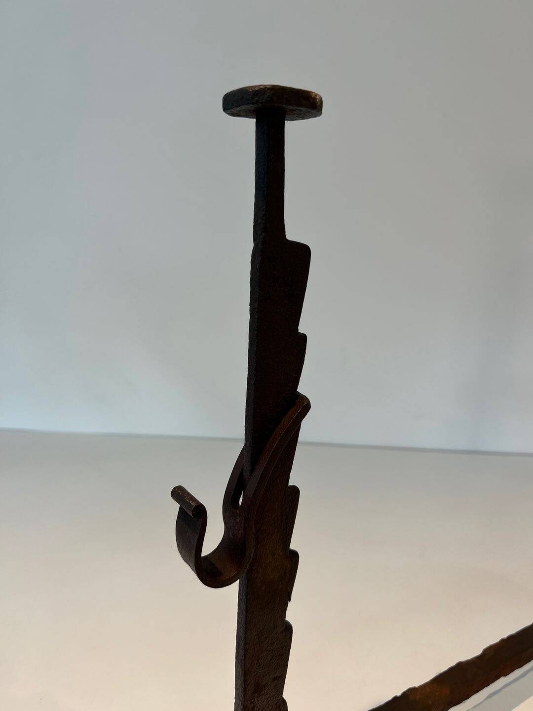 Pair of wrought iron andirons with adjustable supports and tripod feet.