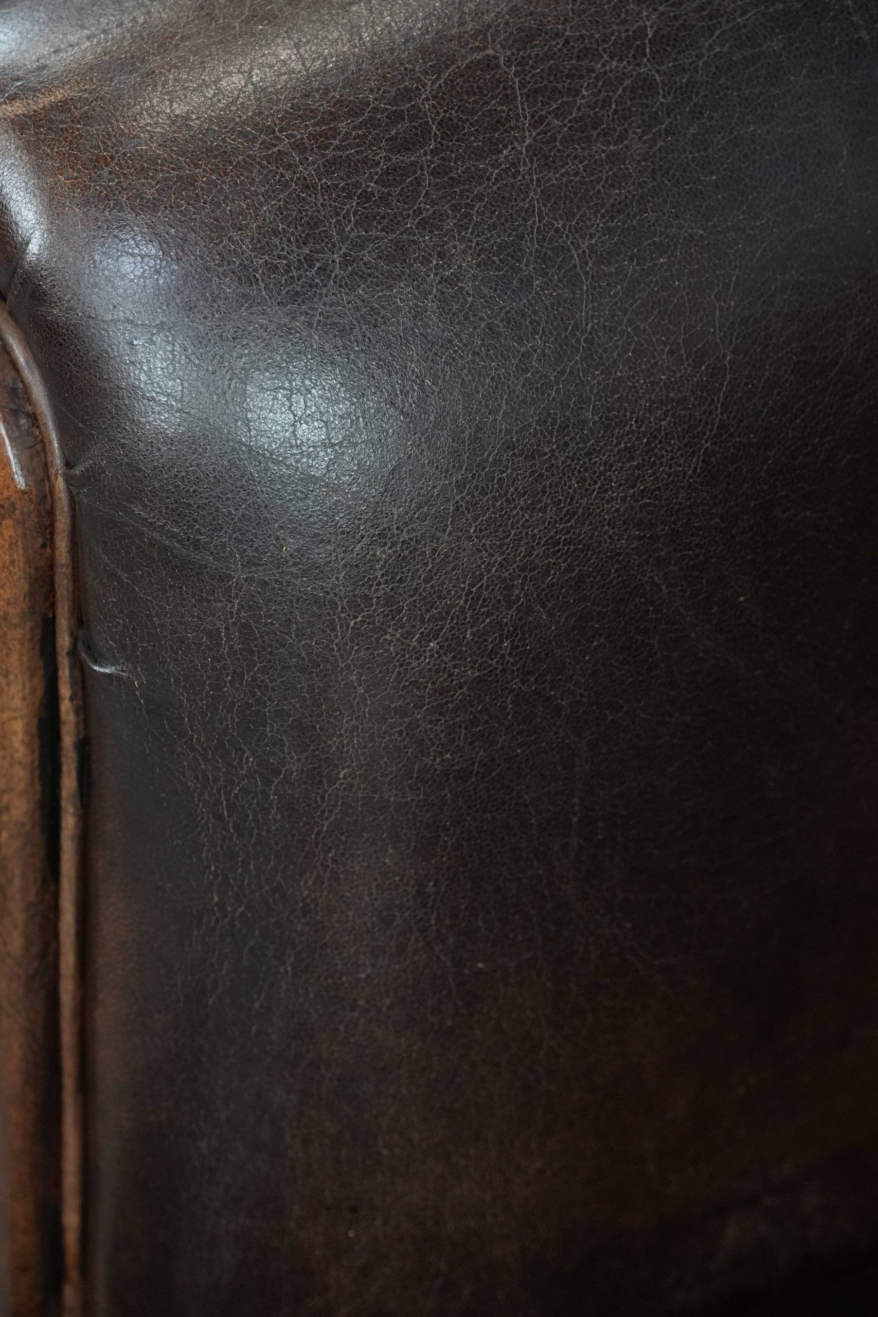 Dark brown vintage club armchair in English style made of sheepskin leather