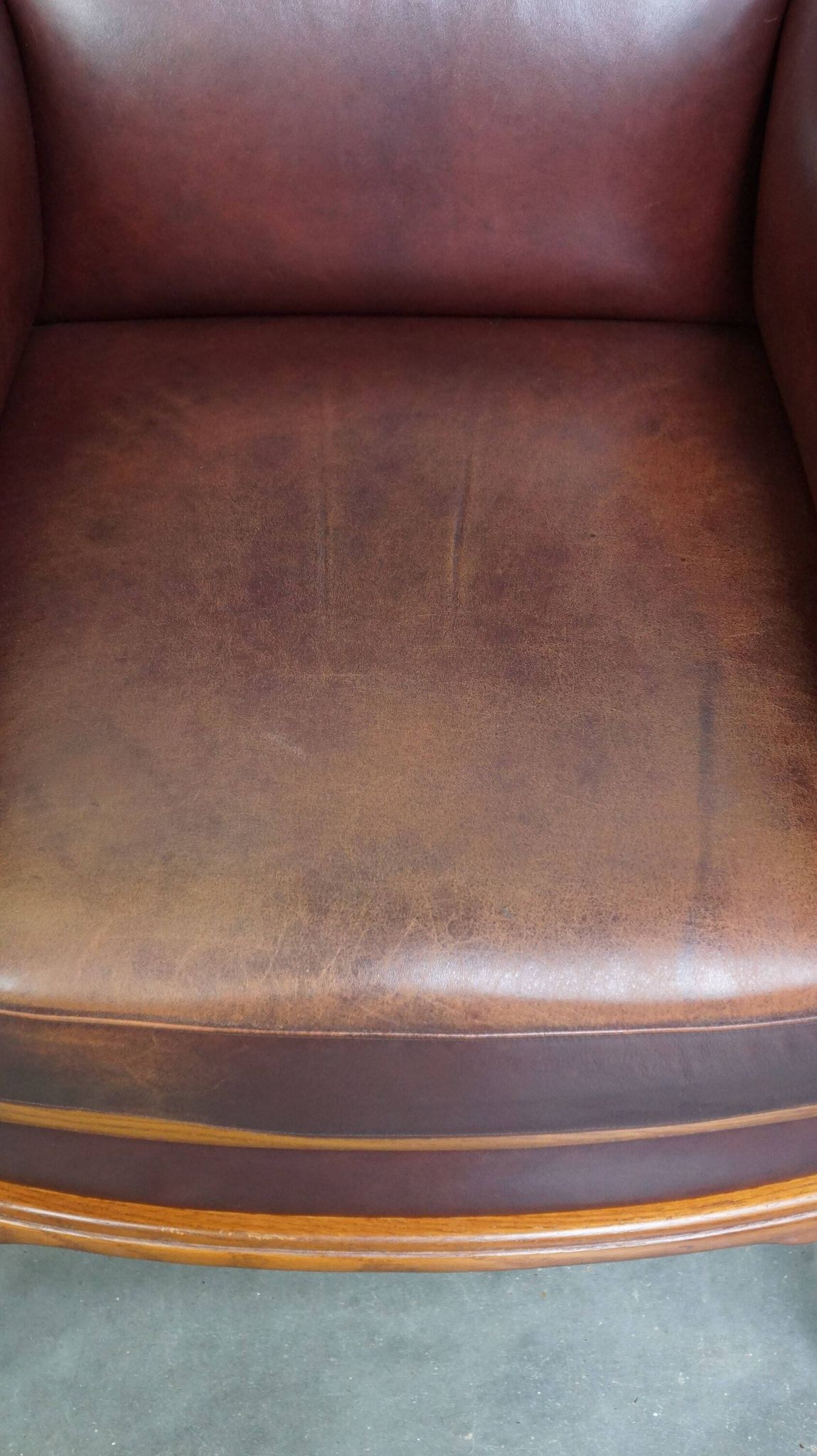 Very comfortable classic cowhide armchair with a high back in a mild Art Deco style