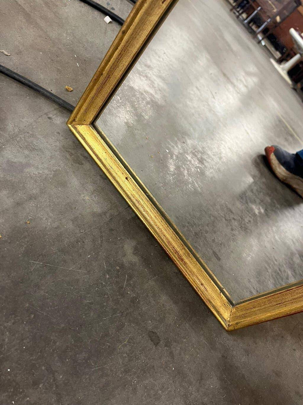 Narrow and tall antique mirror, adorned with golden patterns.