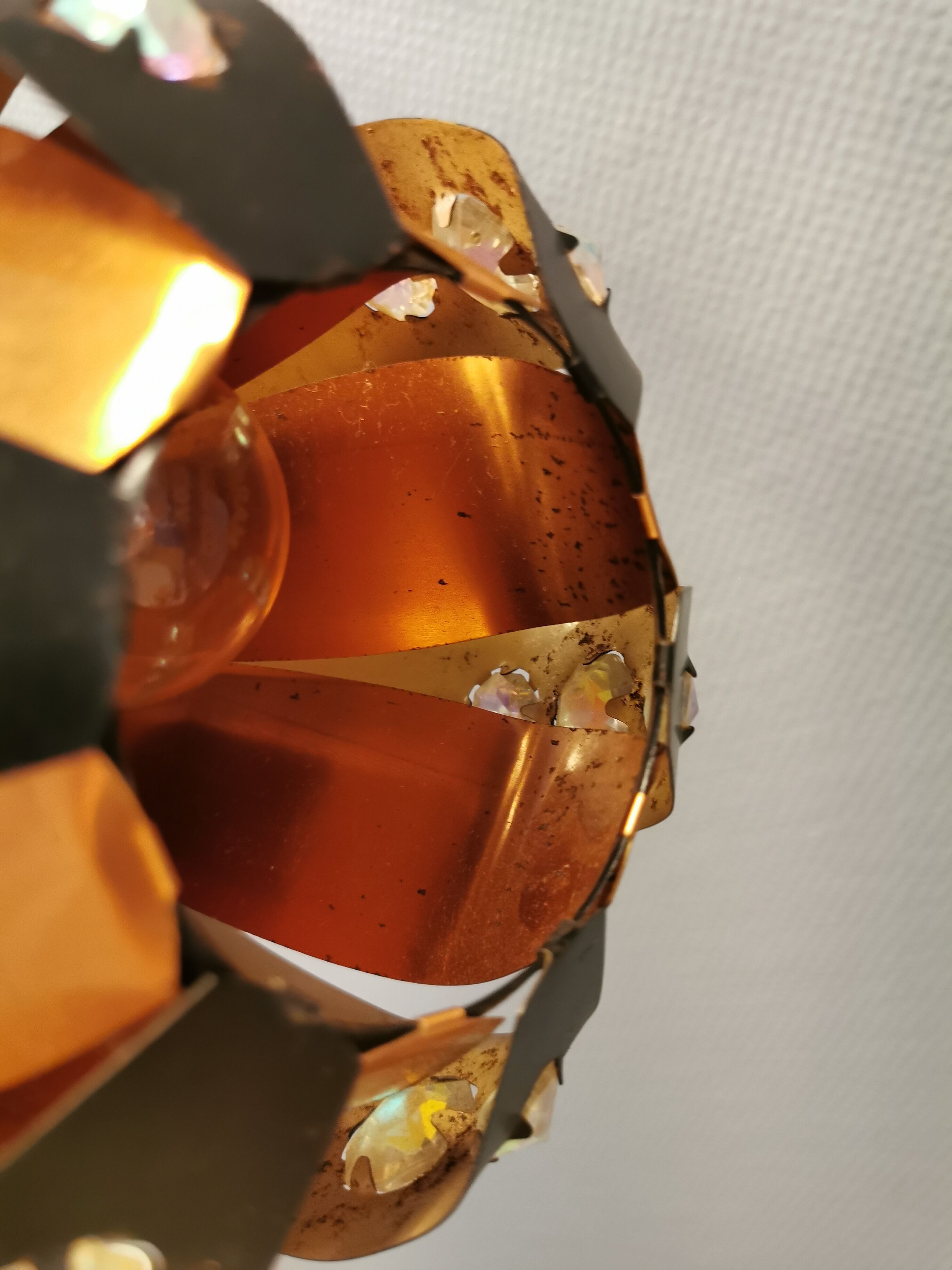 Hanging lamp in thin metal pieces, copper colored and black with prisms.