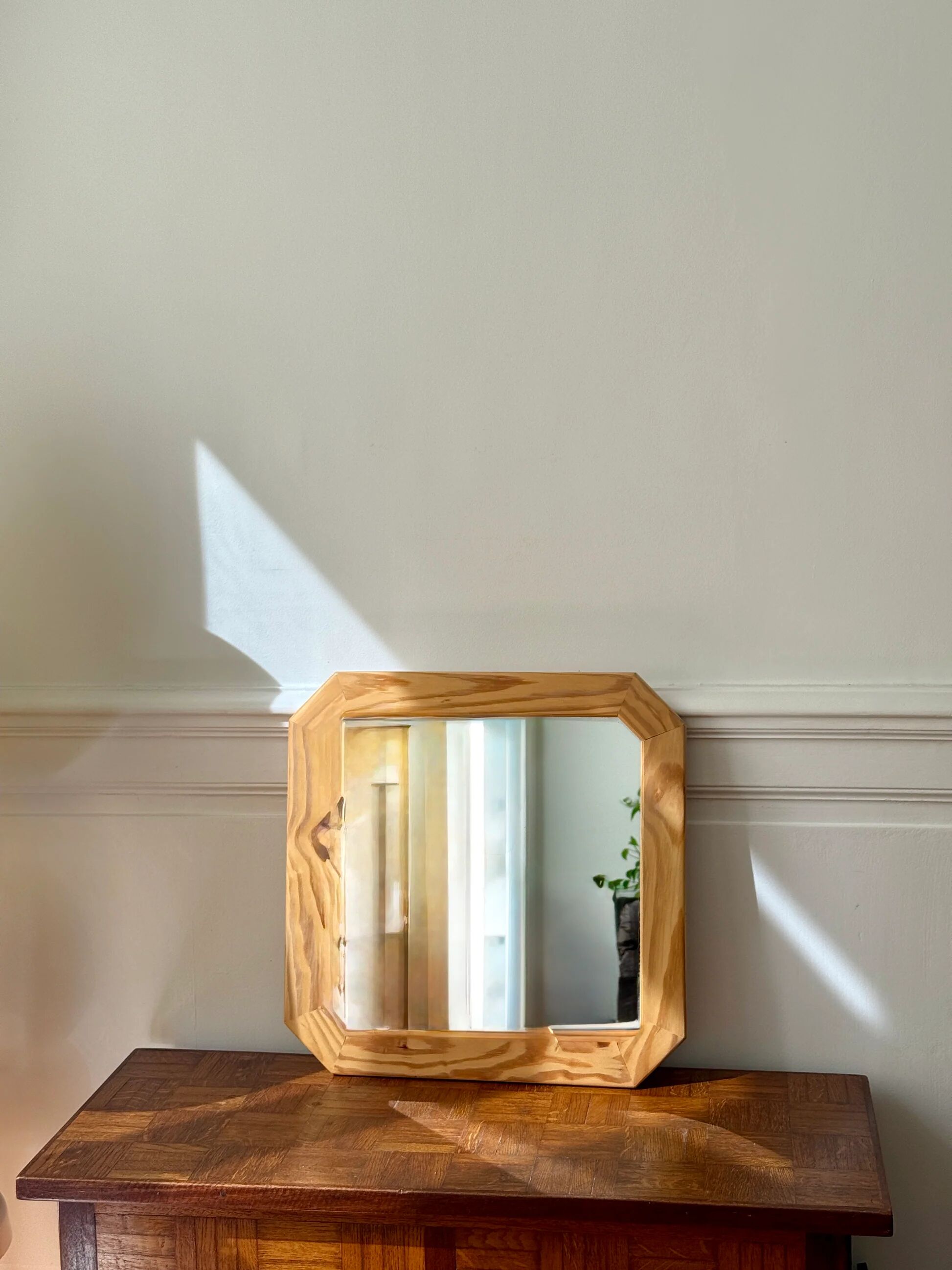 Octagonal mirror in light wood with grooves.