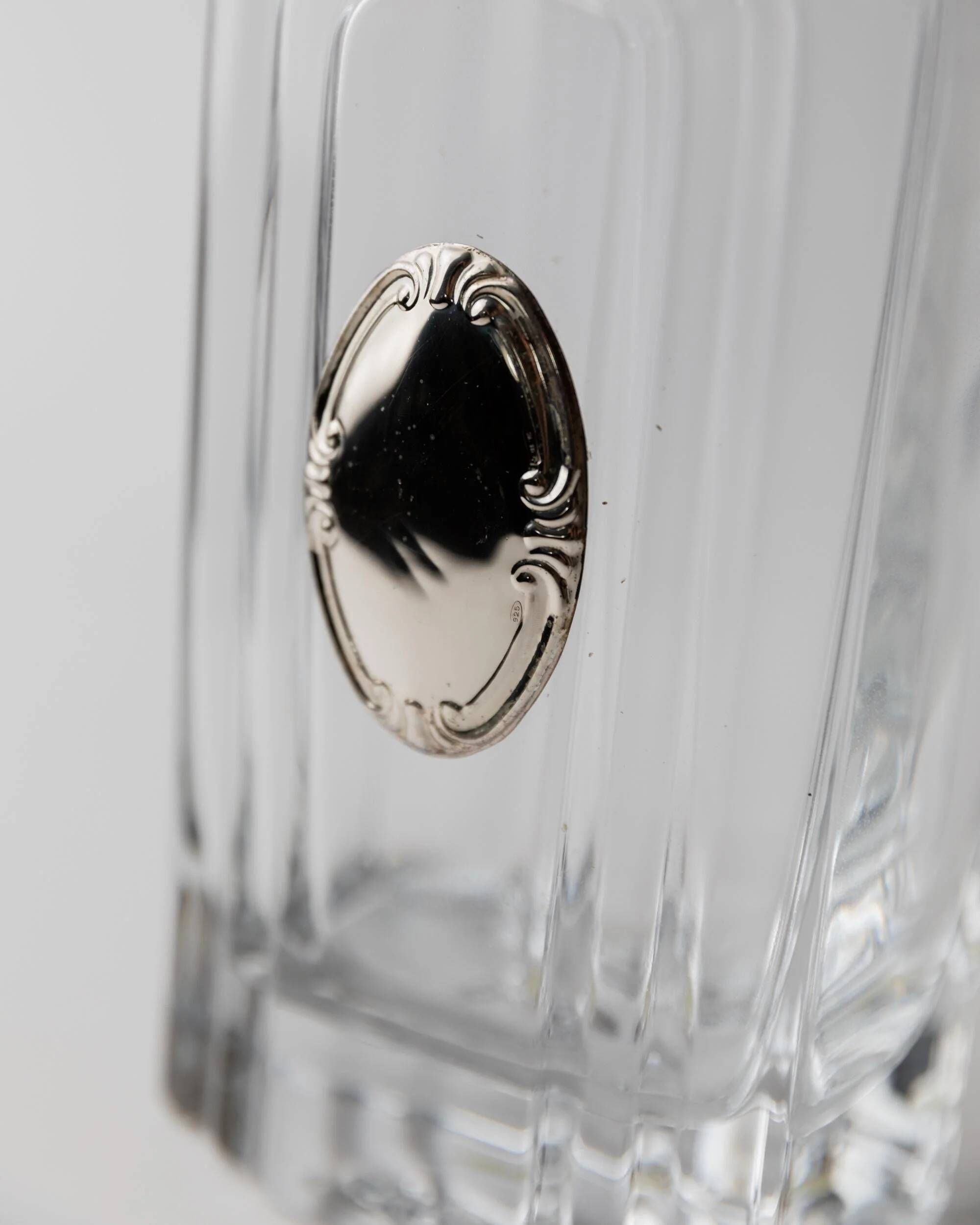 Vintage glass decanter from the 1980s, transparent glass with a silver plate and spherical stopper.