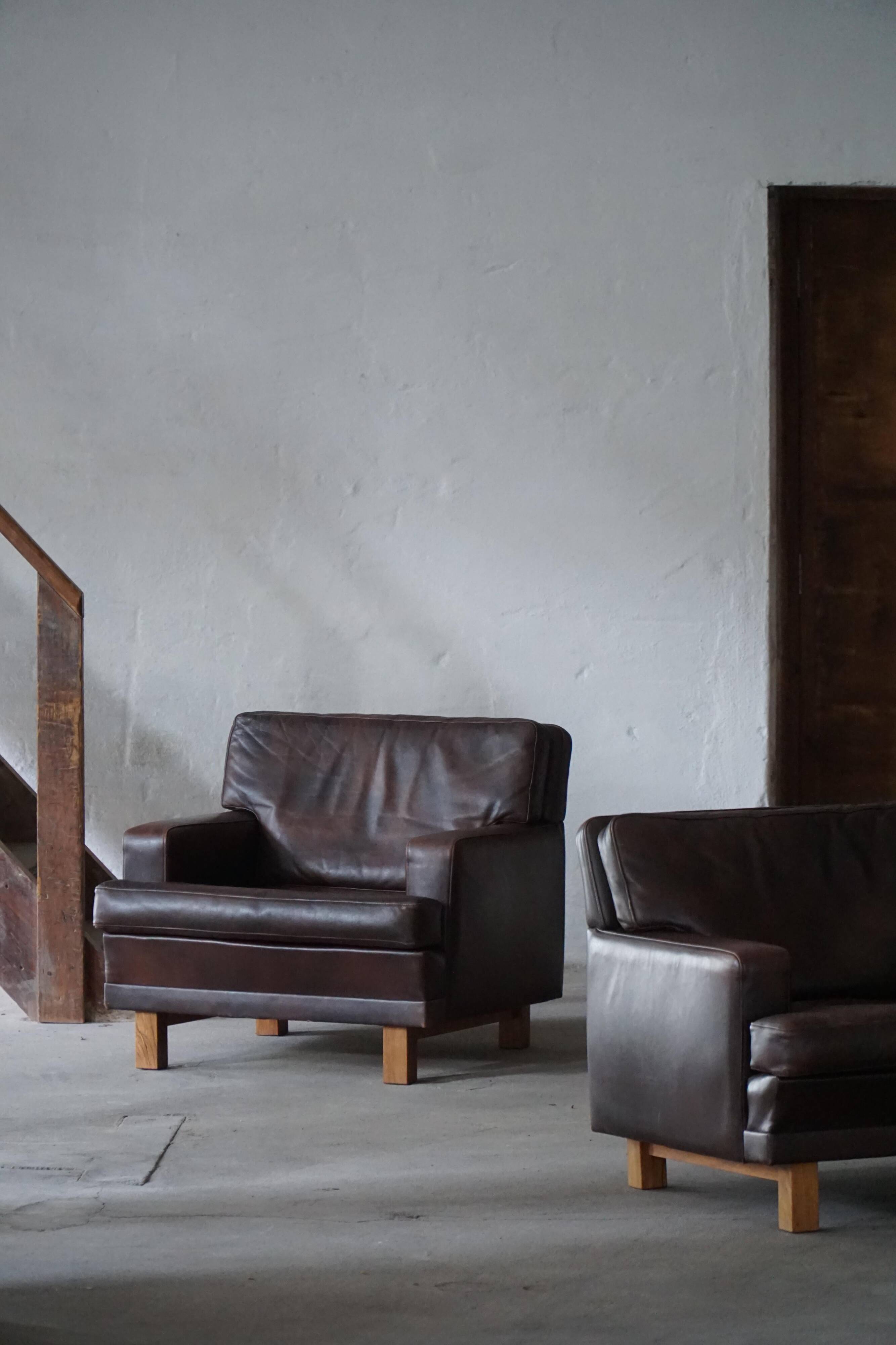 Pair of modern Danish lounge chairs in dark brown leather and rosewood, 1960s.