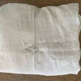 Damask tablecloth with a floral pattern and a central embroidered monogram.