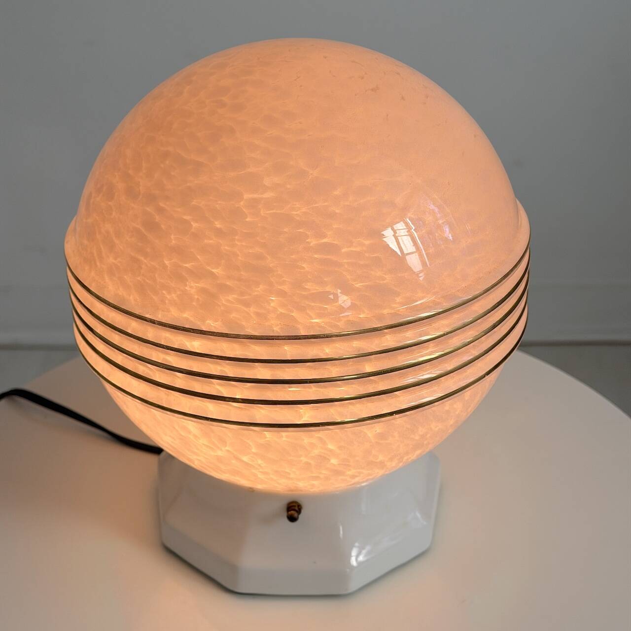 Art Deco lamp with a speckled pink glass globe and a white ceramic base.