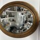 Antique oval mirror in gilded wood, bevelled mercury glass, 19th century.