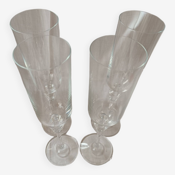 4 crystal champagne flutes with feet decorated with two knots.