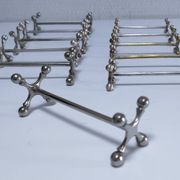 Eleven 70s design metal "crosshair" knife holders
