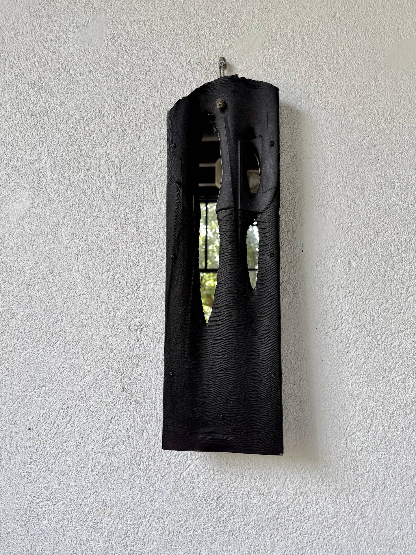 Brutalist hammered mirror, free-form, patinated metal.
