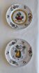 Two earthenware plates with fruits, pears and plums.