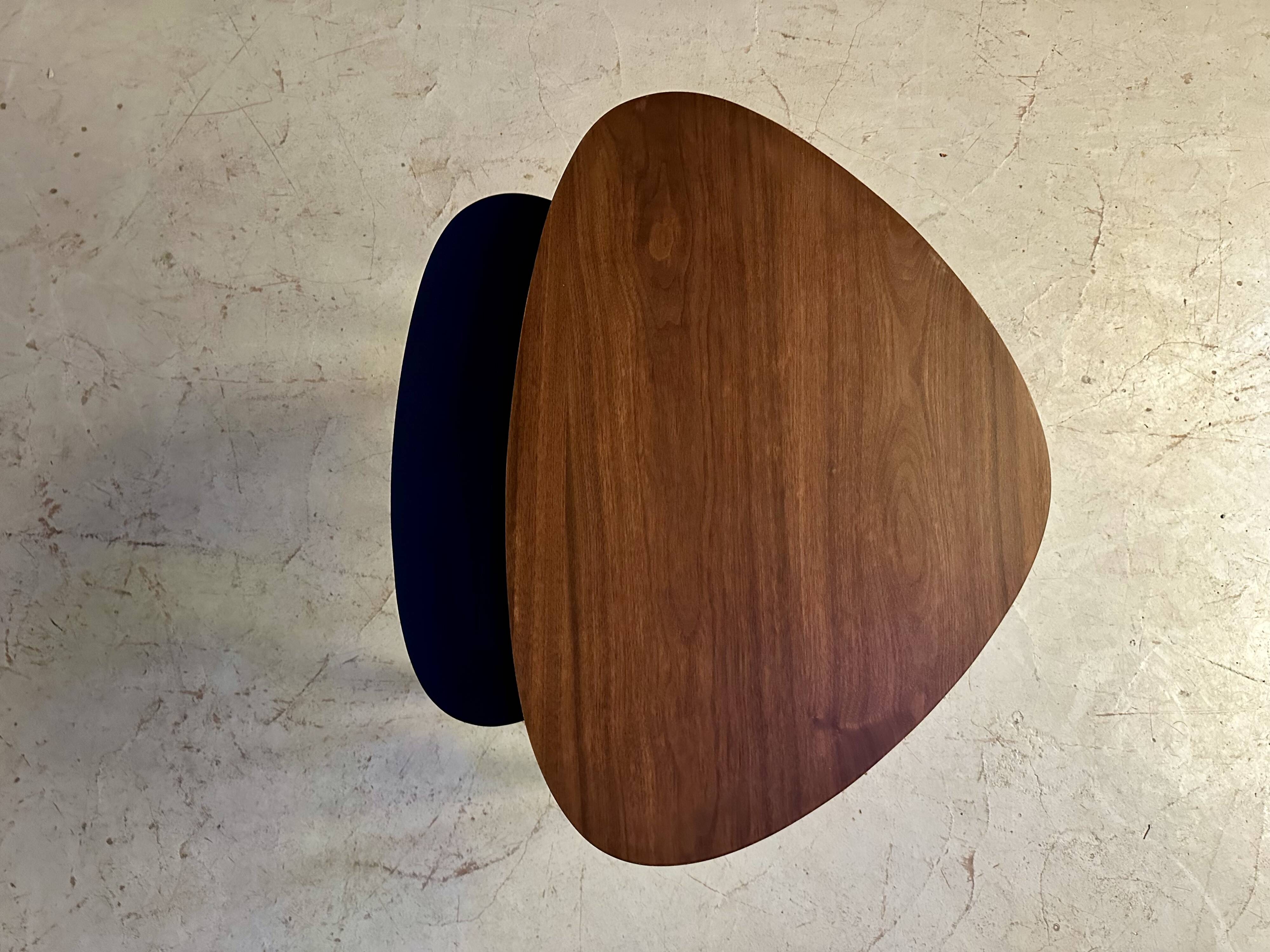 A pair of tripod and nesting coffee tables in walnut and midnight blue.