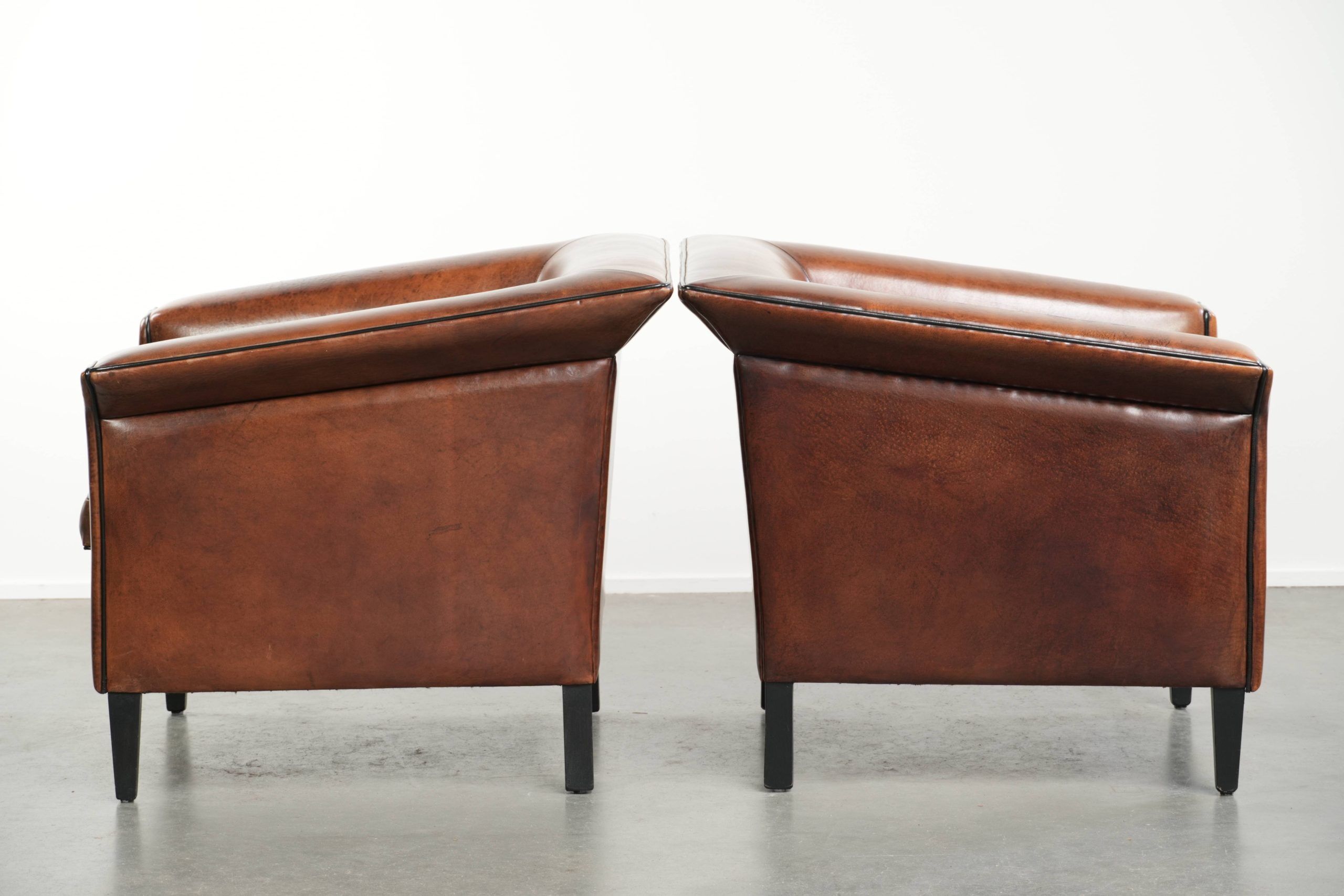 Ensemble de deux fauteuils en peau de mouton au design Art Déco avec passepoil noir.