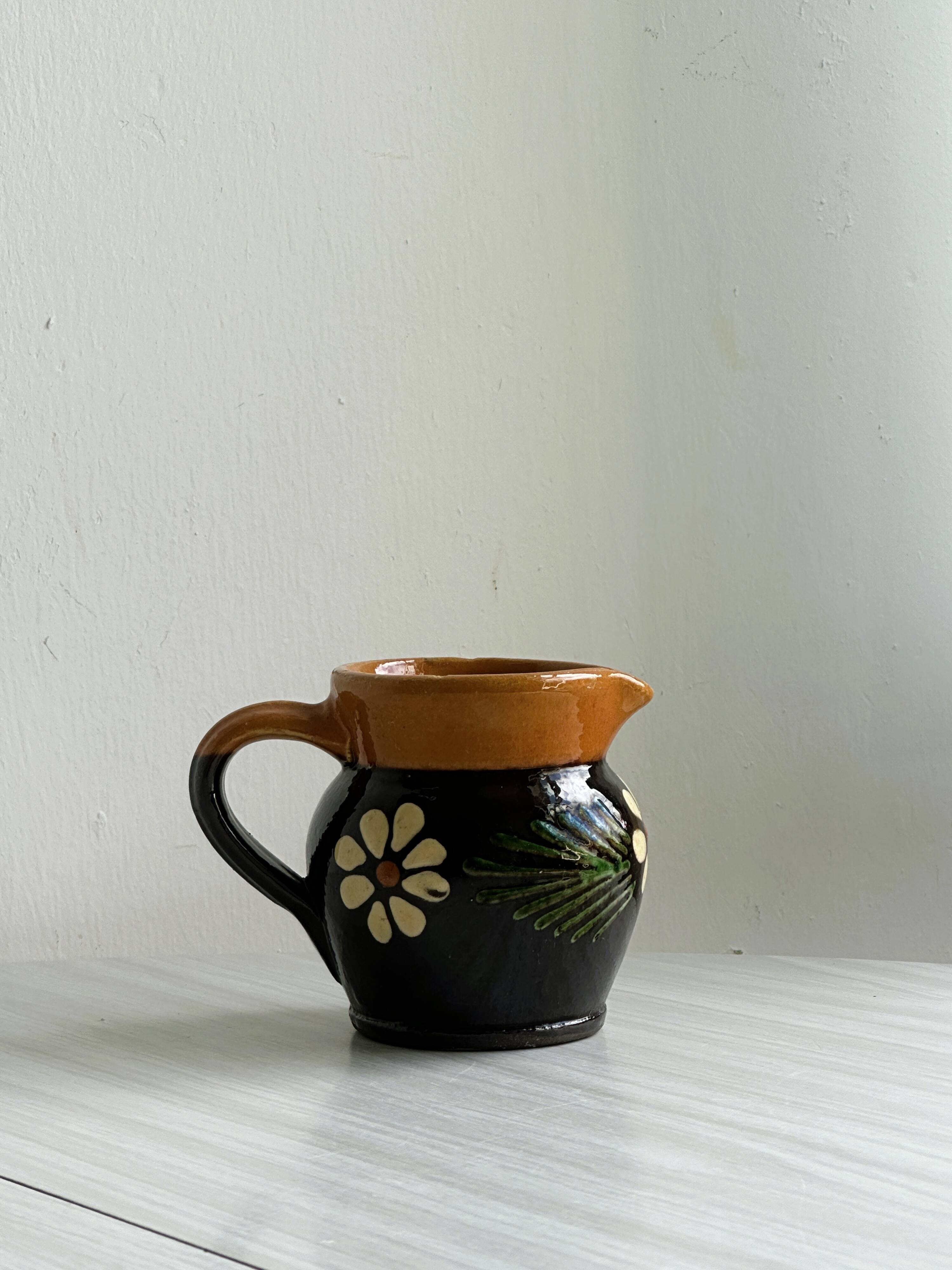 Petit pichet Alsacien en céramique noire et marron, décoré de motifs floraux peints à la main.