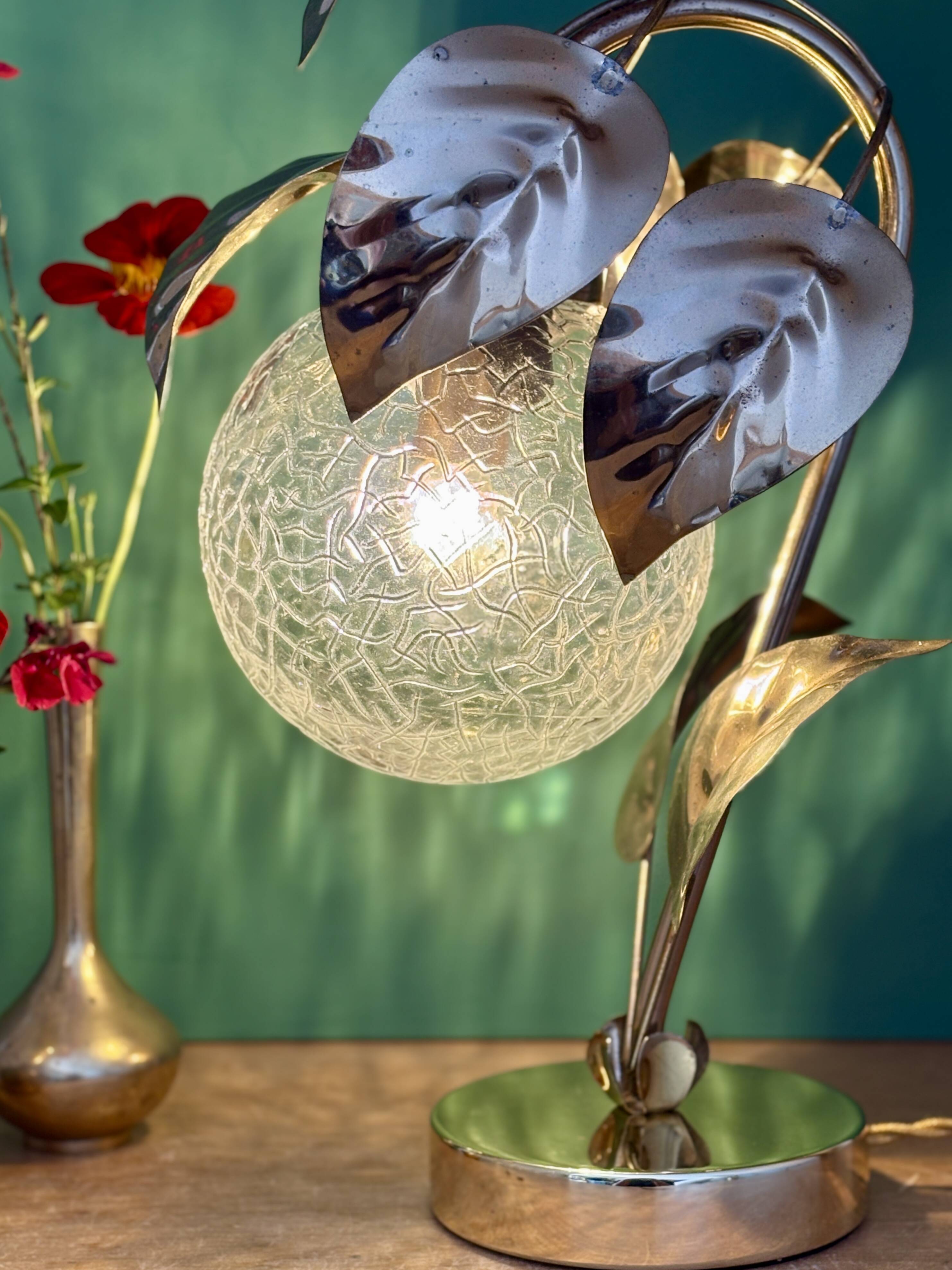 Vintage lamp with brass leaf design and transparent glass globe.