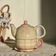 Vintage porcelain teapot and cup set with pink and beige floral and gingham pattern