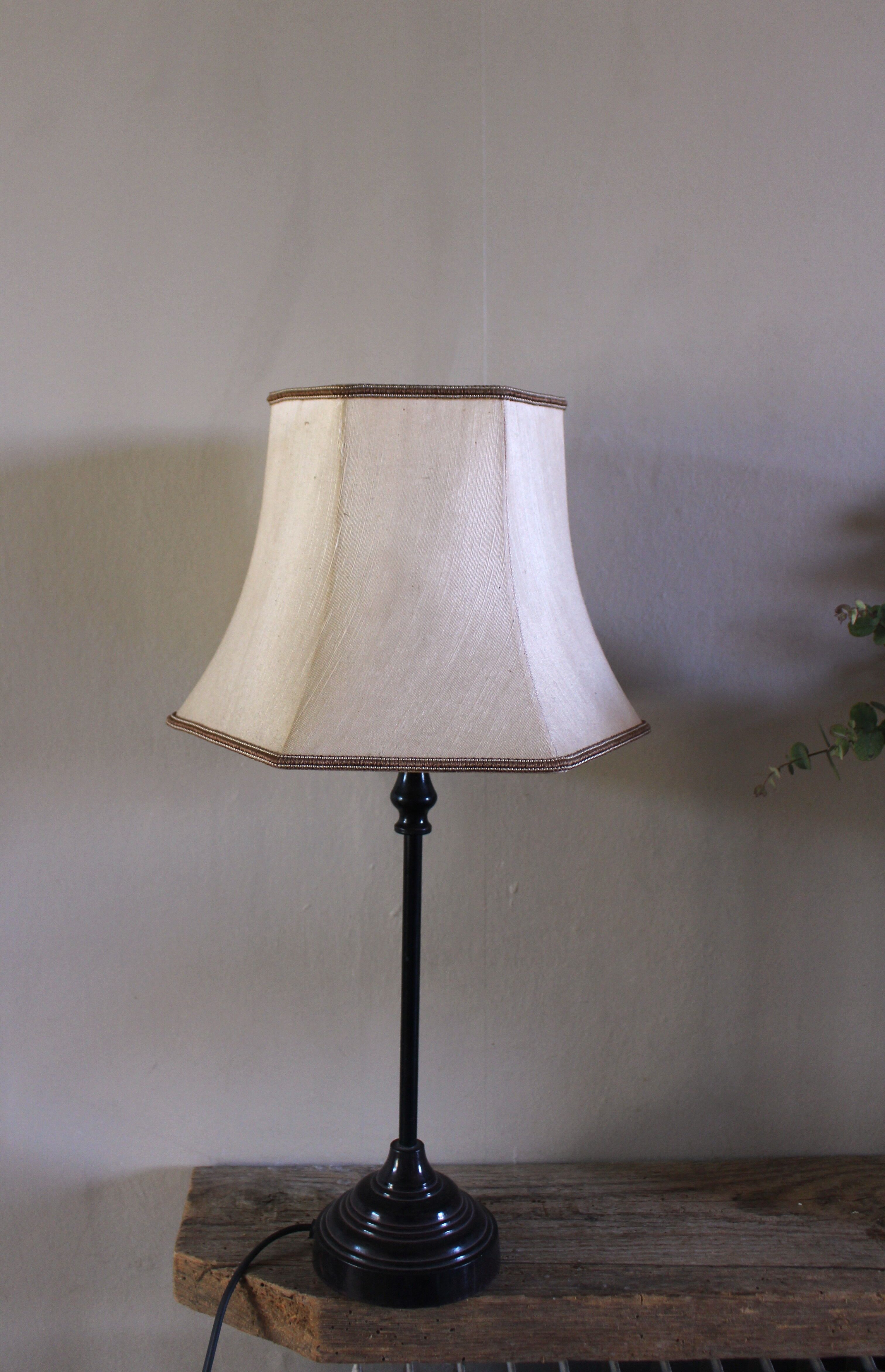 Table lamp with a patinated base and vintage woven shade.