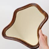 Antique wall mirror in carved wood with a wavy shape and a golden trim.