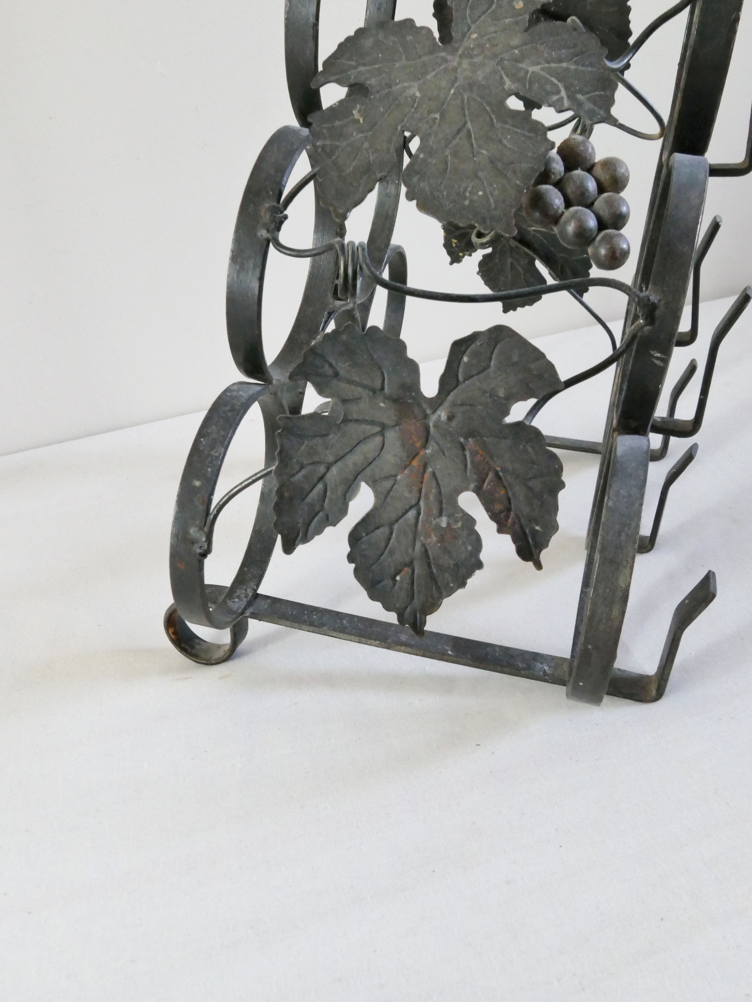 Vintage black wrought iron bottle holder decorated with vine leaves