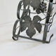 Vintage black wrought iron bottle holder decorated with vine leaves