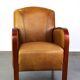 Luxurious cowhide Art Deco design armchair with wooden armrests and cognac-colored leather