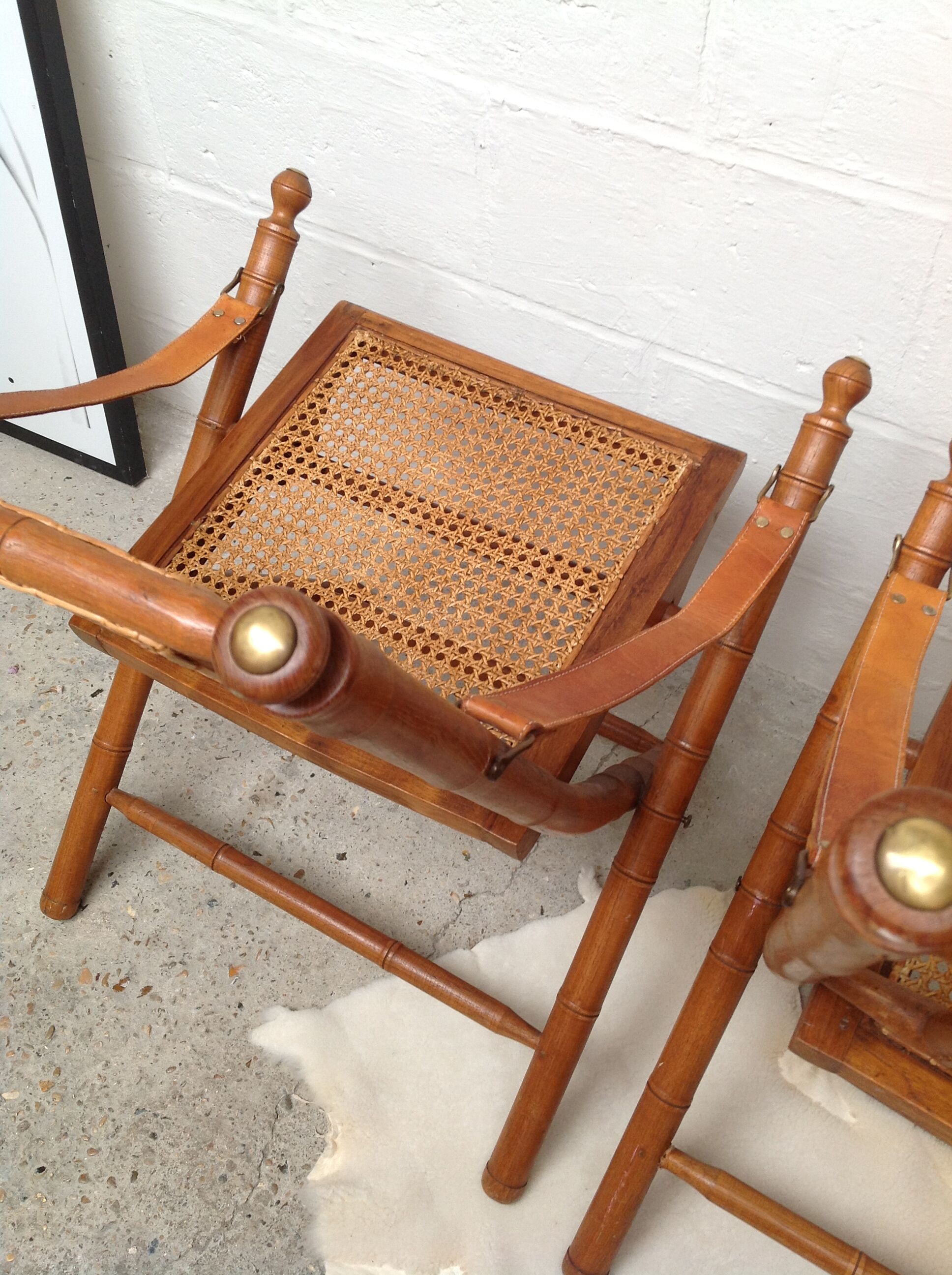 Pair of folding chairs in bamboo and caning, leather and brass