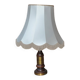 Vintage brown and gold desk lamp made of carved wood and brass, with a fringed shade.