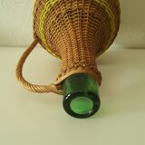 Vintage glass bottle covered with hand-woven wicker and scoubidou, with a handle