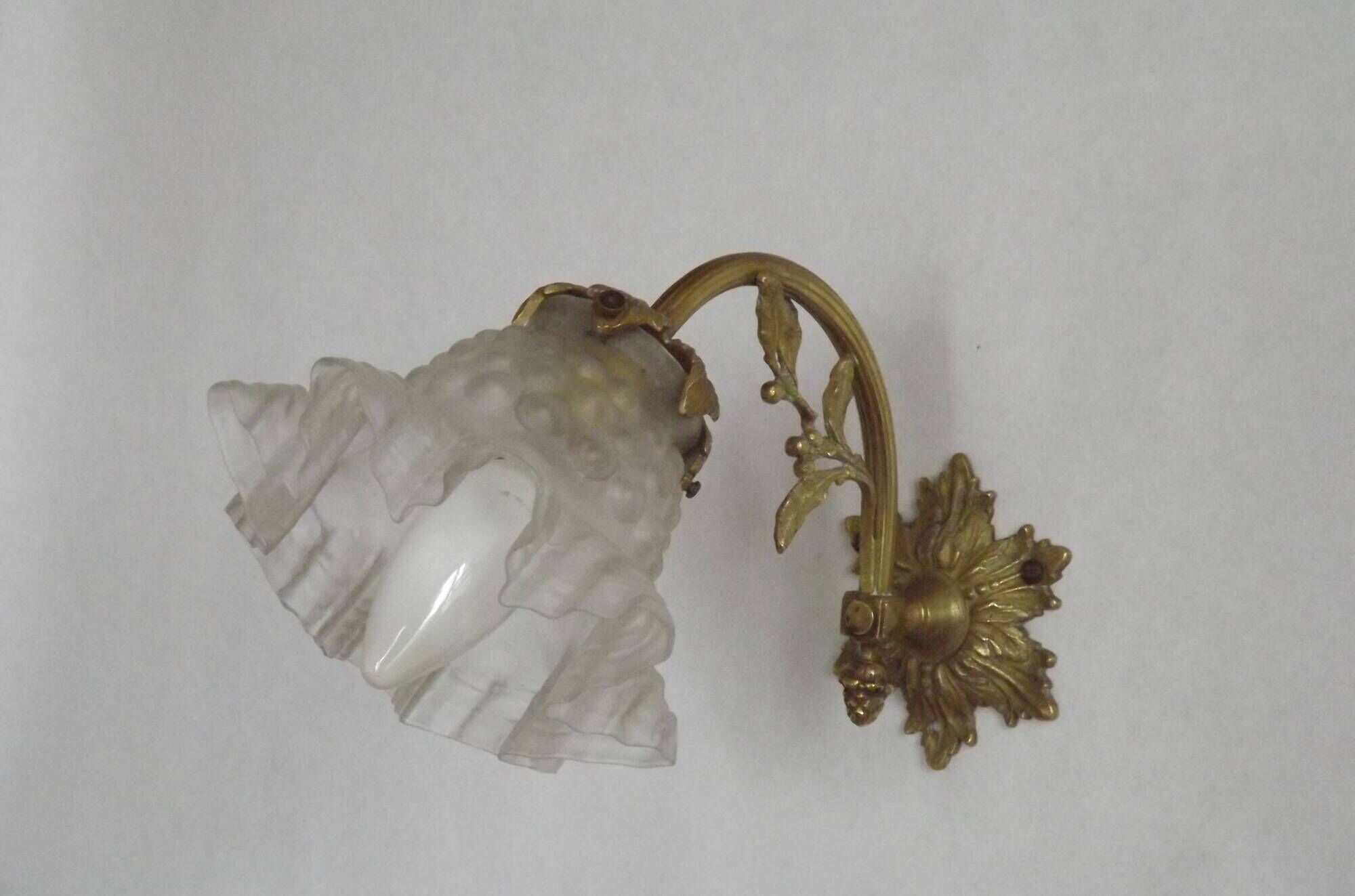 Simple wall sconce in French Art Nouveau bronze with a white glass shade featuring patterns.