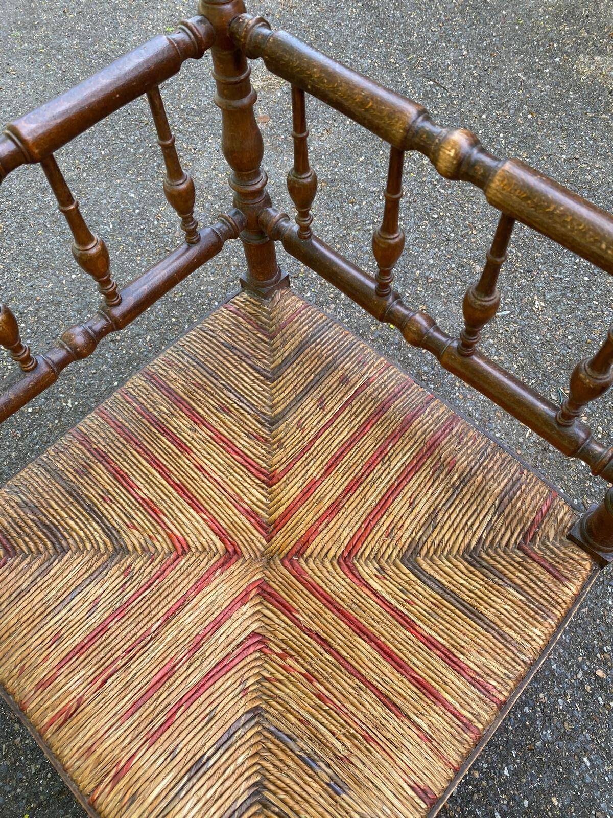 19th-century solid wood corner chair with red and blue rush seating.
