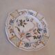 Flat plate in earthenware, hand-painted rural decoration partly in relief,