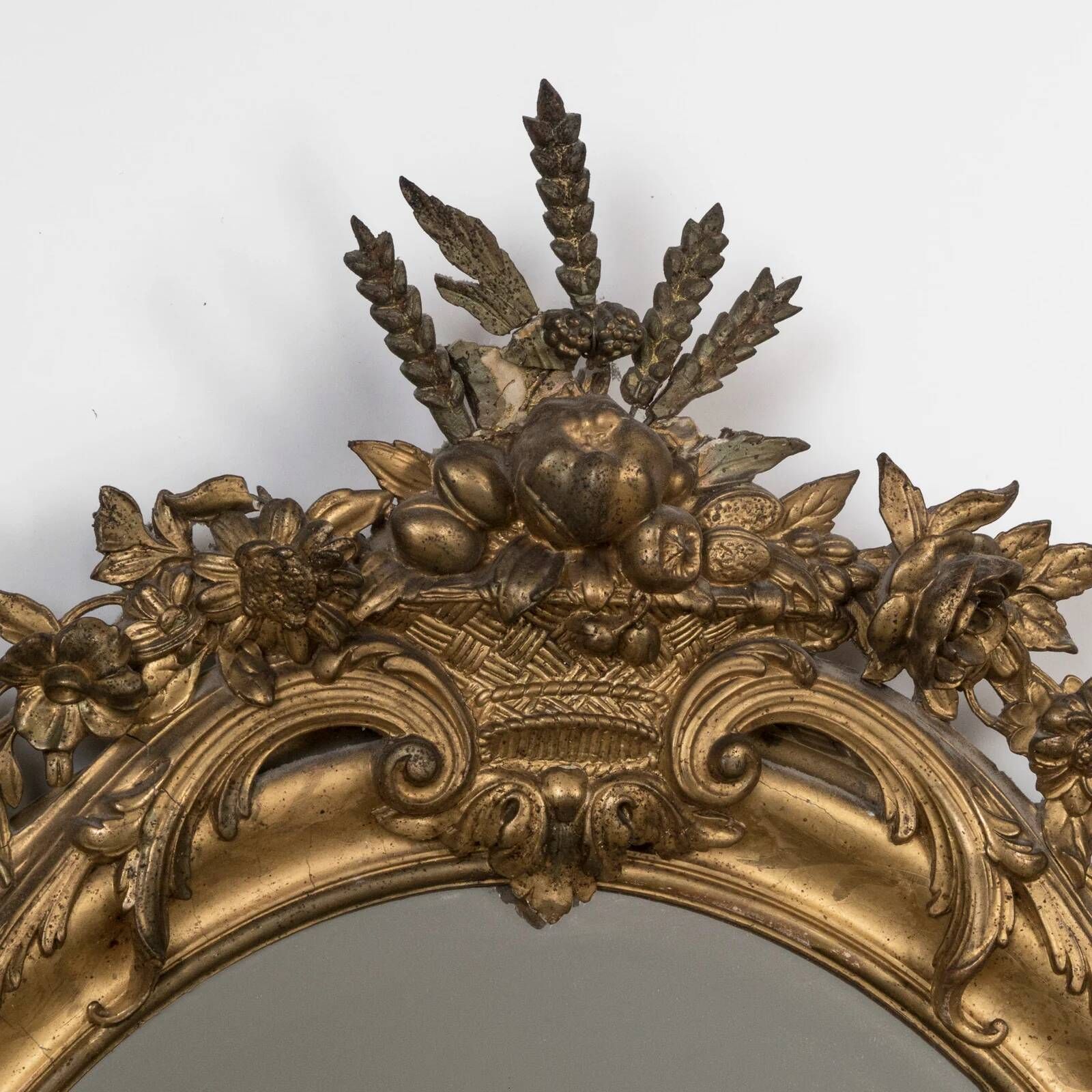 French 19th-century oval mirror in gold leaf with a pediment.